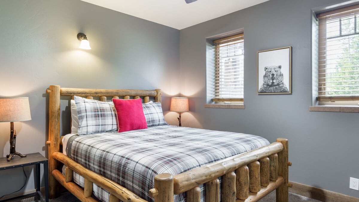 Bedroom 1 on the first floor offers a comfortable and inviting place to rest, with a Queen-sized bed that features a plush comforter and a luxurious mattress. The Handmade Lodgepole bed provides a warm and inviting atmosphere.
