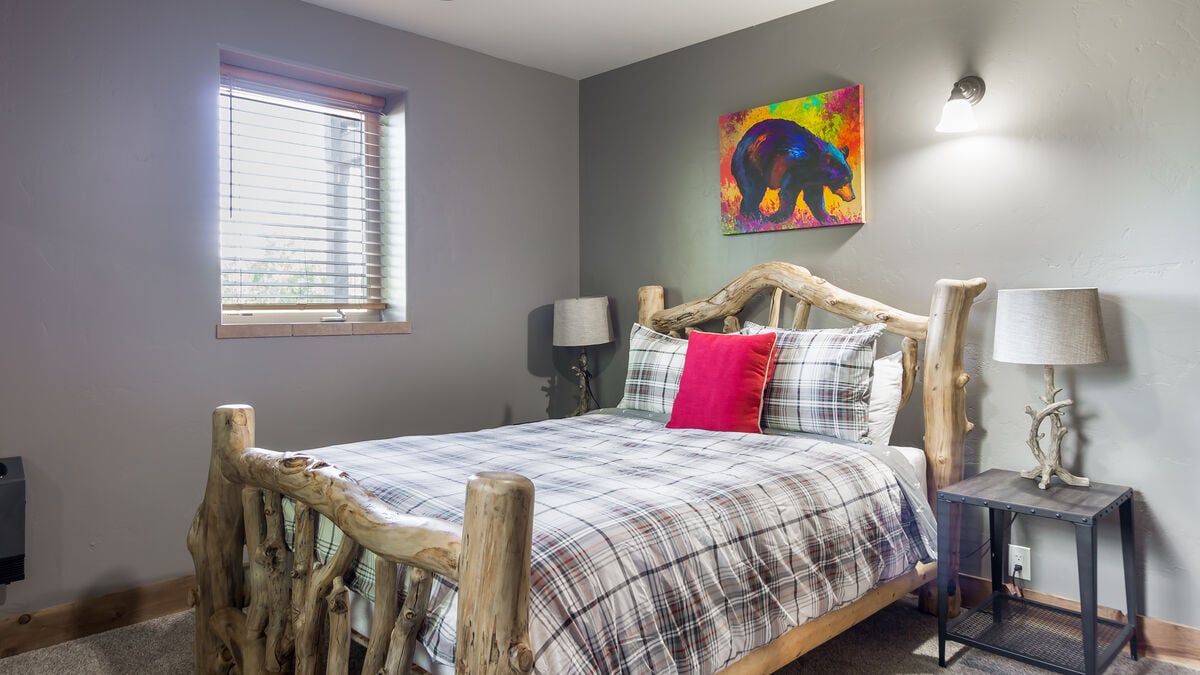 Bedroom 2 on the first floor offers a comfortable and inviting place to rest, with a Queen-sized bed that features a plush comforter and a luxurious mattress. The Handmade Lodgepole bed provides a warm and inviting atmosphere.