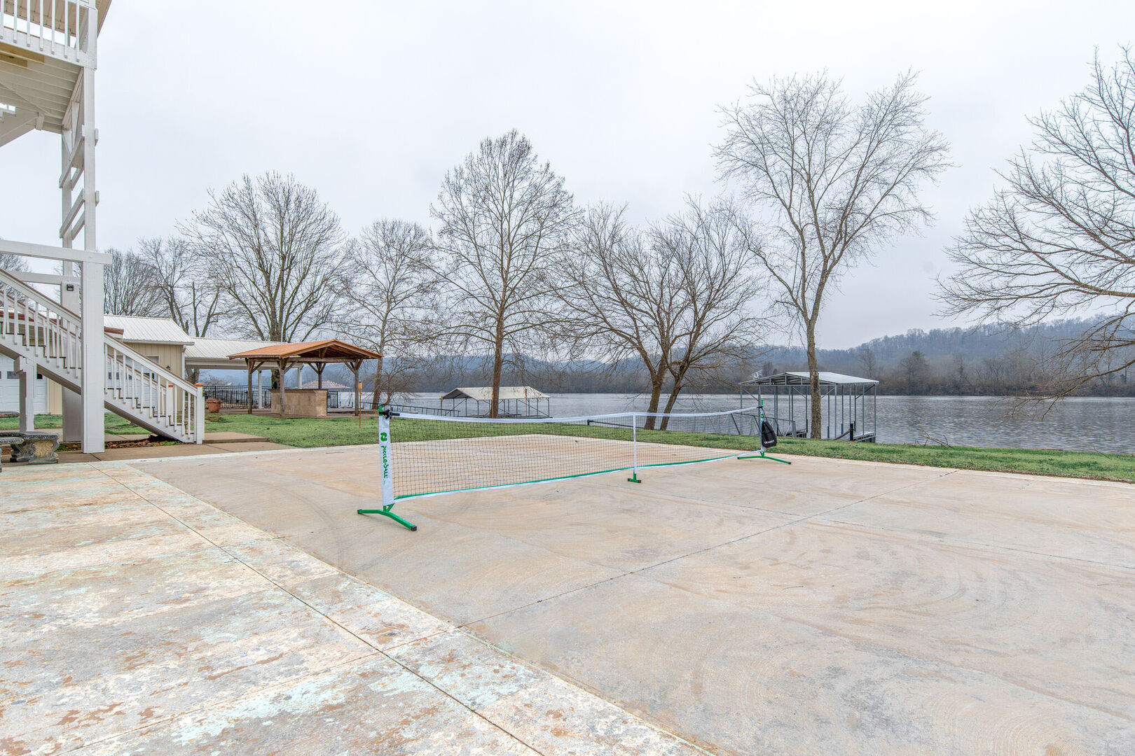 Riverfront property with private dock, BBQ grill, basketball hoop, tennis/pickle-ball net, and fire pit.