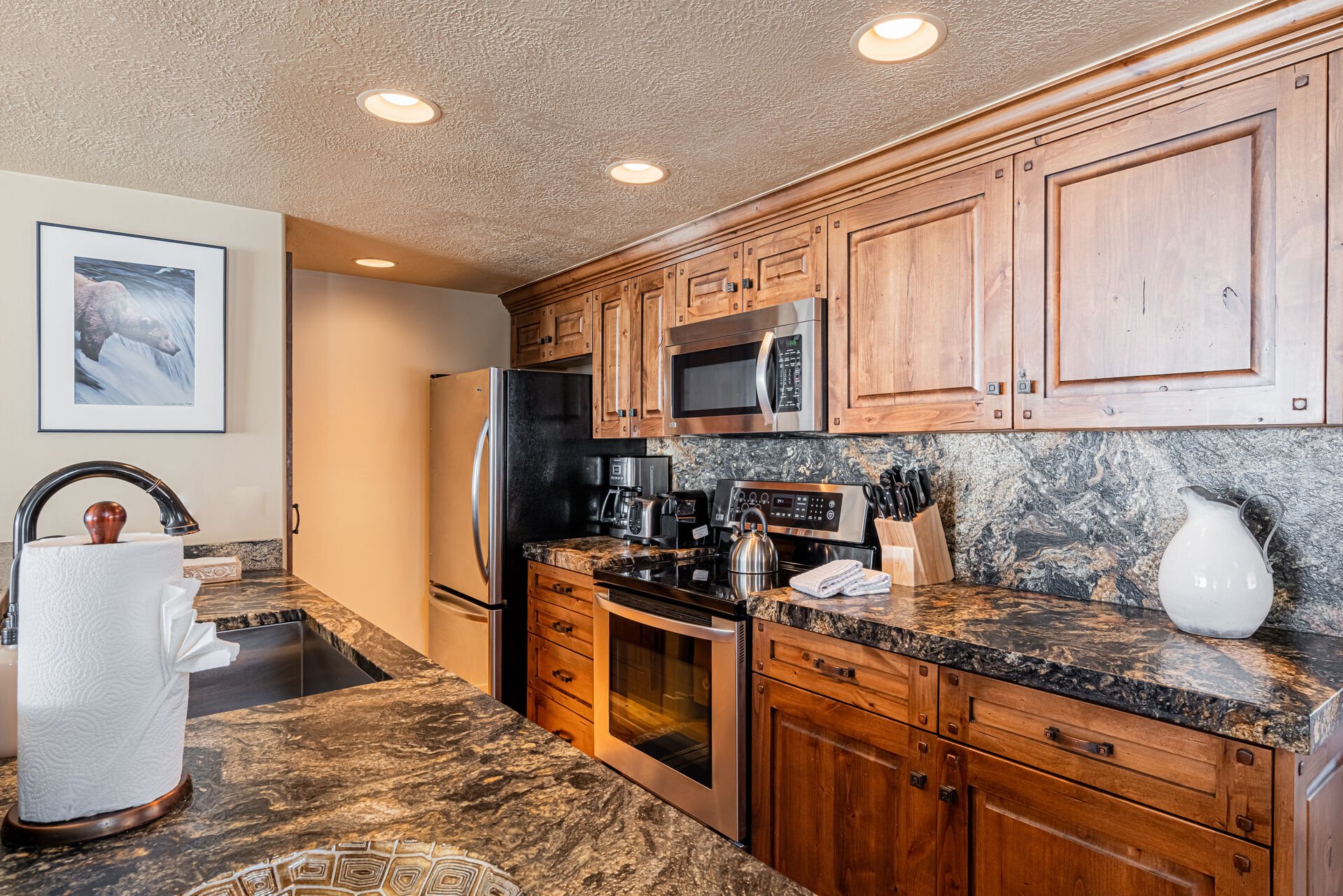 Fully Equipped Kitchen with gorgeous stone countertops, stainless steel appliances, and bar seating for 3