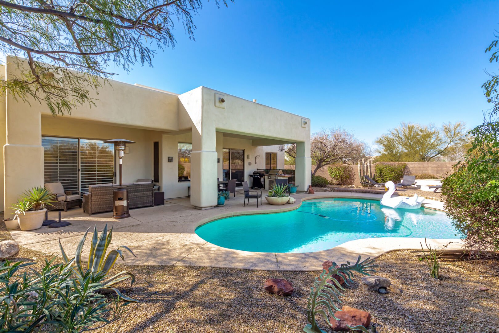 Private Backyard featuring Sparkling Blue Pool, Sun Loungers, Fire Pit, BBQ Grill, and Covered Patio with Space Heater and Lounging Areas.