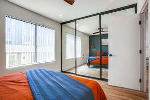 Guest bedroom with queen bed with ceiling fan and large, mirrored closet