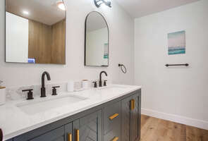 Across from the guest bedroom is the full guest bathroom with dual vanity, ample storage space and bright lighting