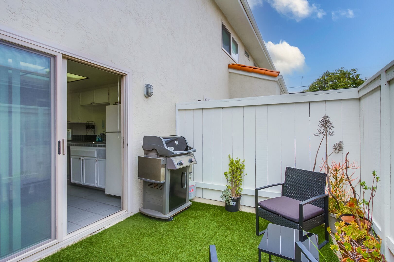 Patio space with dog-friendly enclosed turf area, propane grill, table and chairs and plenty of beach accessories