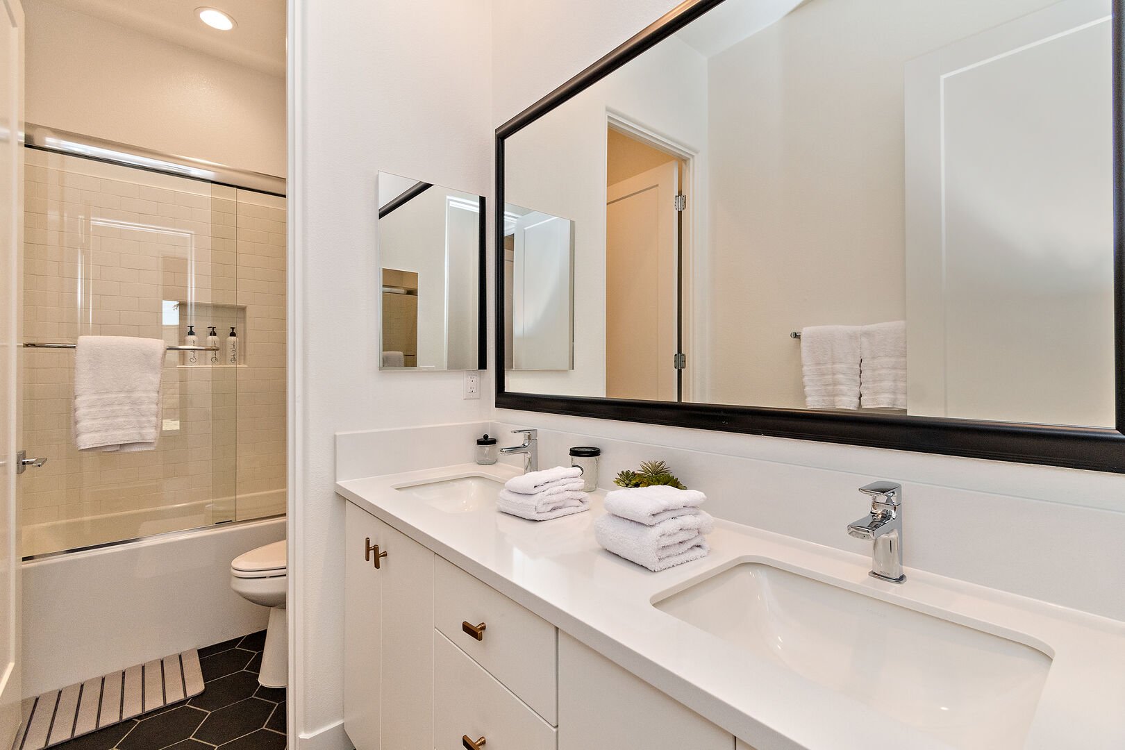 The hallway bathroom is located across bedroom two and features a bathtub, shower combo, and two vanity sinks.
