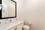 The powder room is located across the laundry room and features a vanity sink.