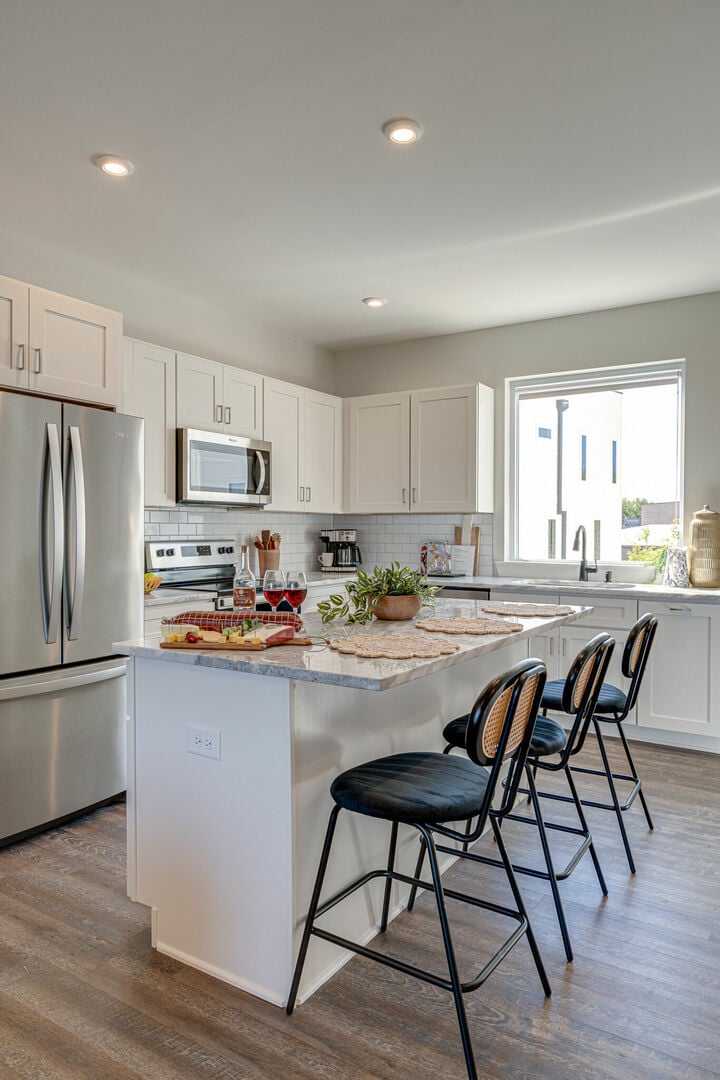 Open kitchen with stainless steel appliances, large island, breakfast bar seating, and is fully equipped with your basic cooking essentials.