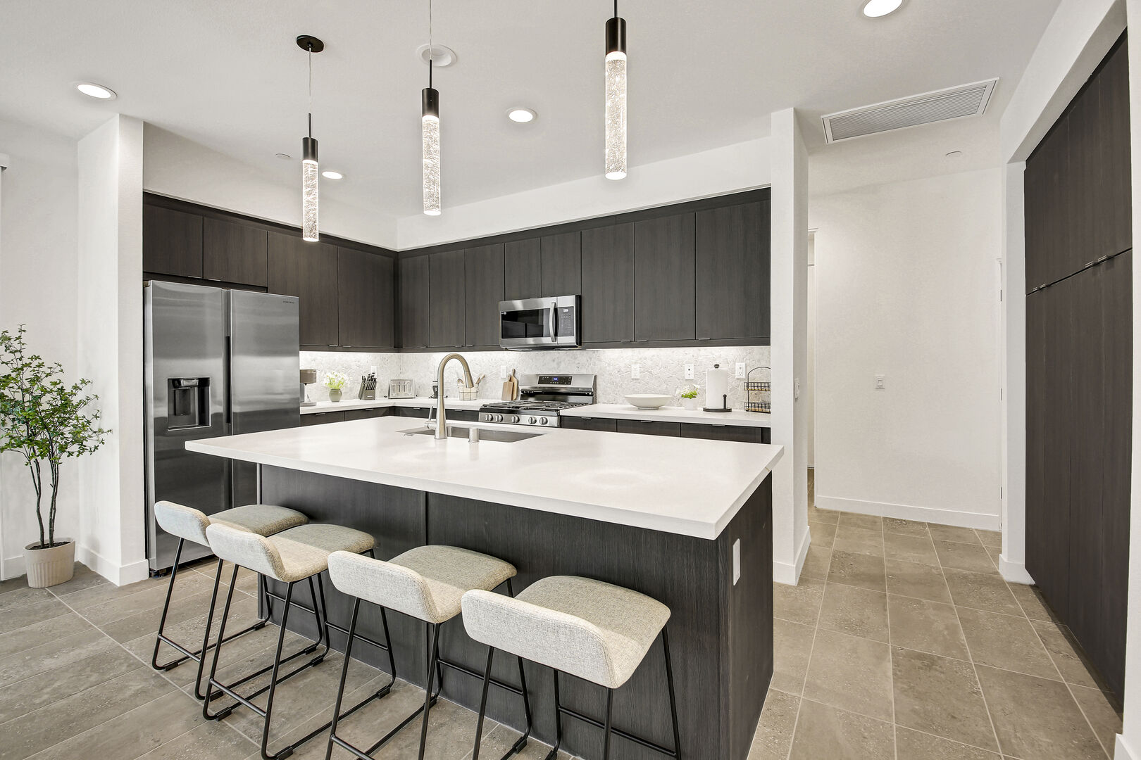 The fully-equipped kitchen features stunning stainless steel appliances, such as a Samsung side-by-side refrigerator with a water and ice dispenser.