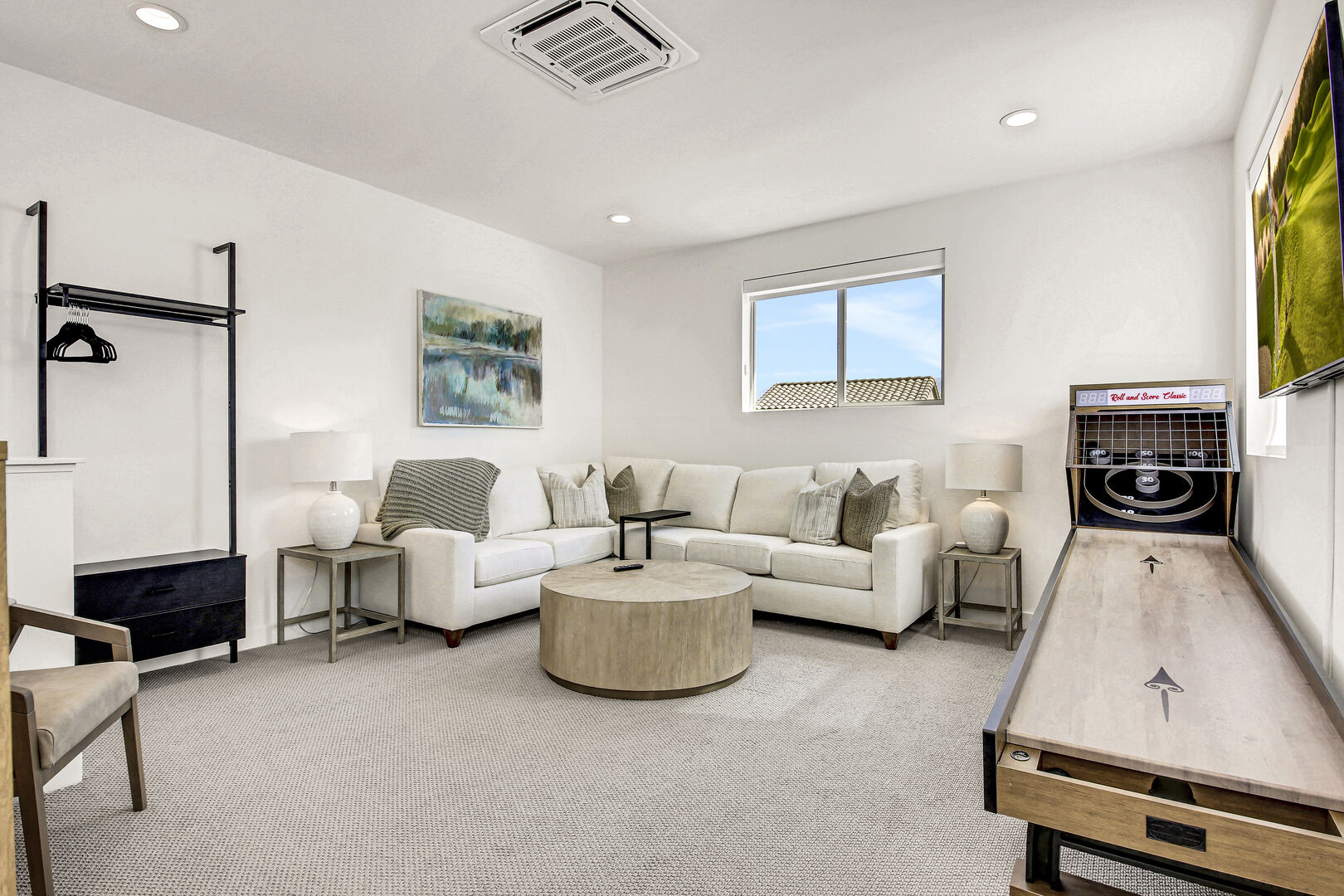 The upstairs landing area features a Queen-sized Sofa Sleeper, 55-inch Samsung Smart television, freestanding garment rack with drawers, couch with seating for six, ceiling-mounted Mini-Split, and a skee-ball machine.