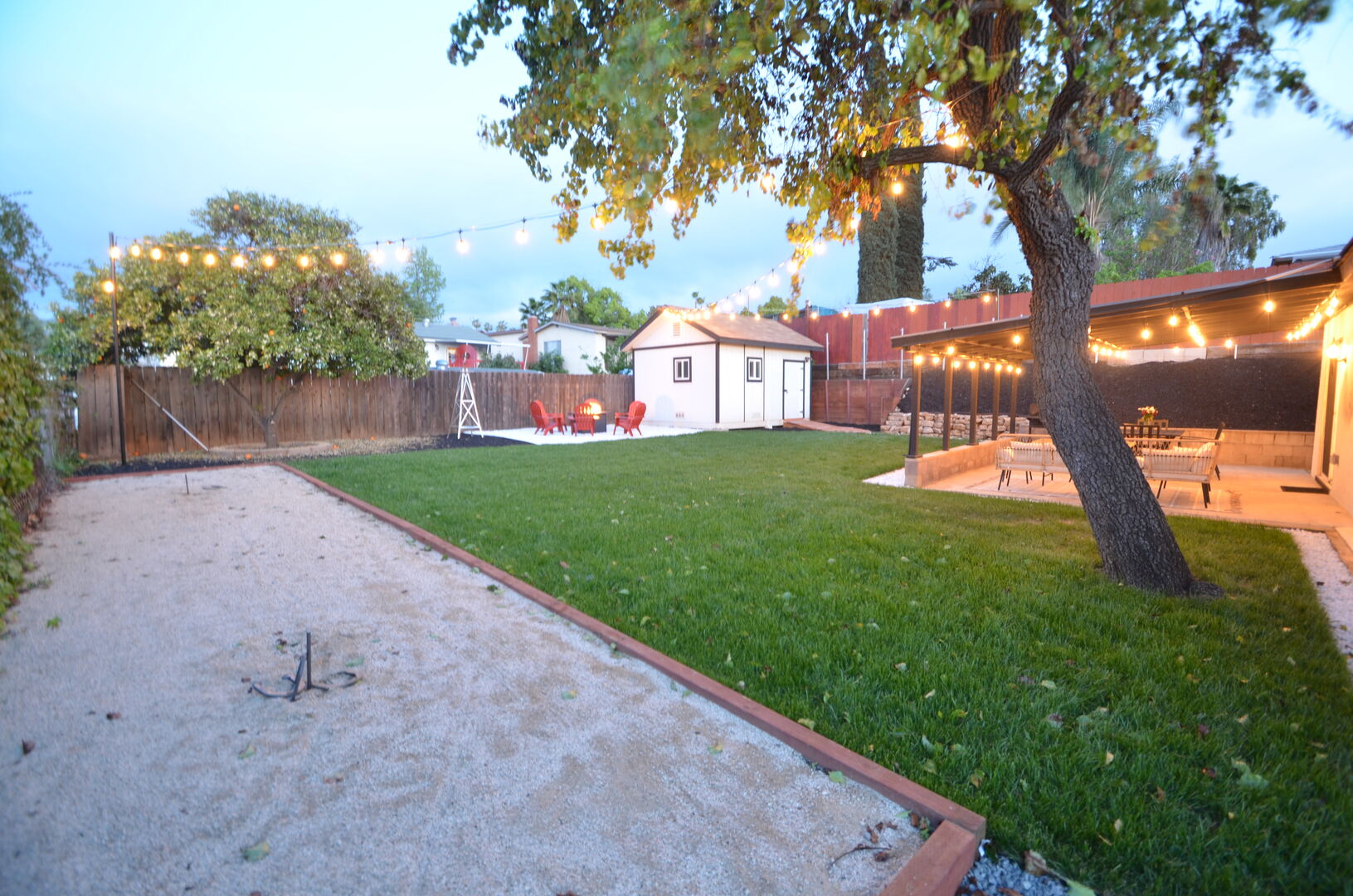 Backyard with sand pit, fire pit, fruit trees, grass and string lights