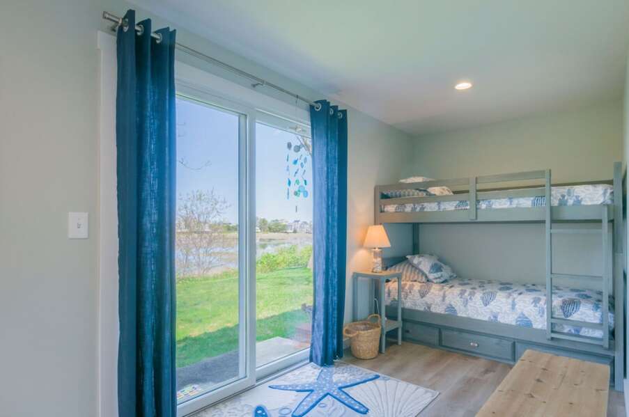 Bunk room with two twins and a slider leading to the back yard with views.