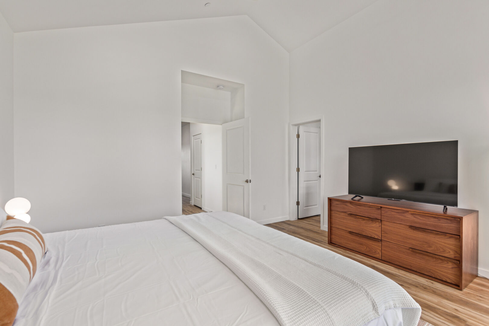 Primary bedroom with King bed, balcony, smart TV, large walk-in closet, and en-suite bathroom.