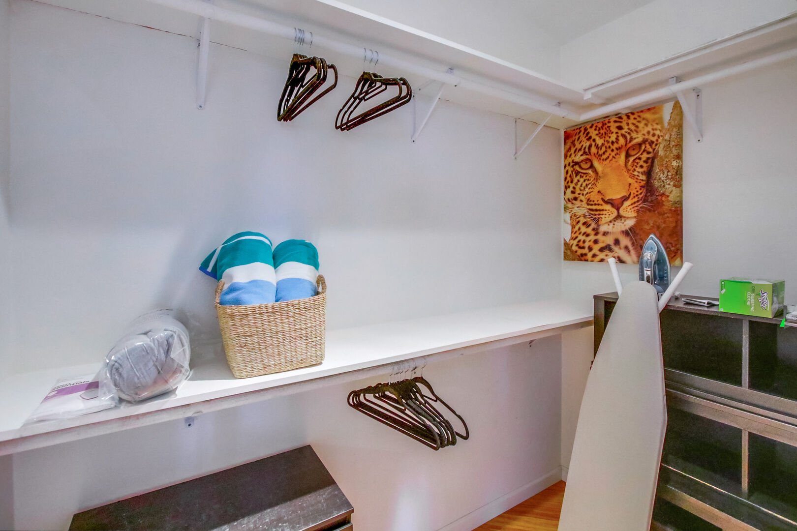 Large walk-in closet with iron, ironing board, hangers, extra linens and towels and ample storage space