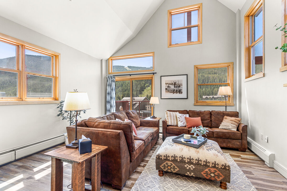  ️ A spacious and cozy living area featuring vaulted ceilings, a warming fireplace, and stunning views of the slopes and village.  