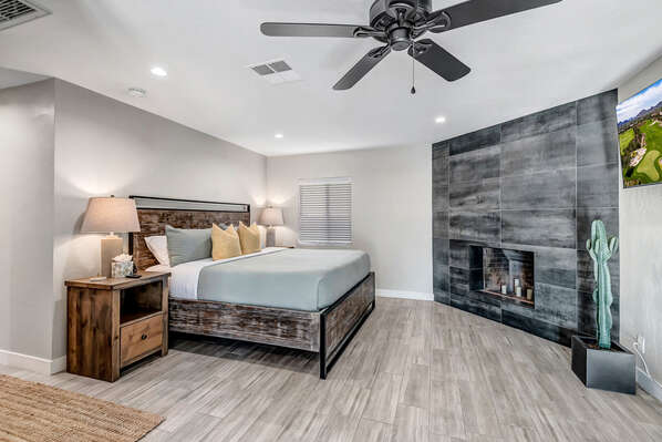 Master bedroom with king size bed, Smart TV, decorative fireplace, desk area and back yard access