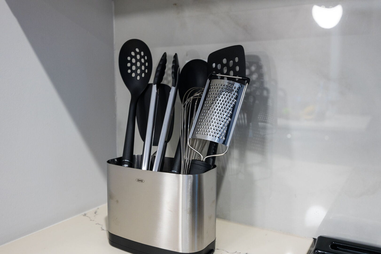 Fully equipped kitchen with stainless steel appliances, basic cooking essentials, toaster, coffee machine, and kitchen island seating.