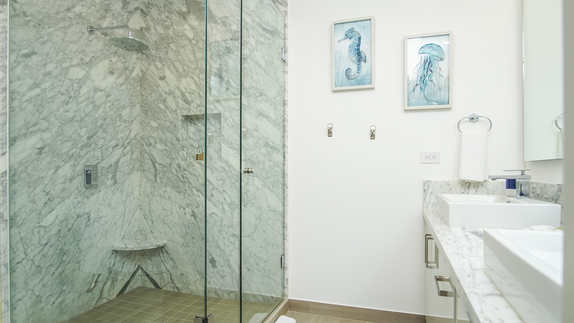 Detail of the main bathroom. Glass enclosed, marble walled shower and vanity with large mirror.