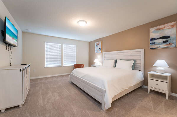 Master bedroom features king size bed, wall mounted flatscreen TV and casual chair