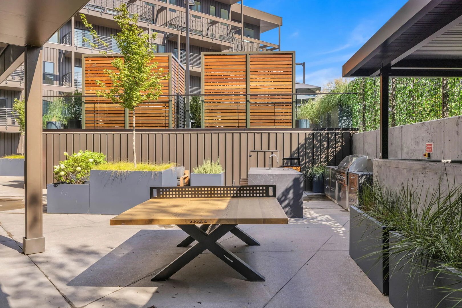 Communal Area: Outdoor furnishings for lounging with a firepit, Ping Pong, and built-in BBQ grill with an outdoor island offering bar seating.