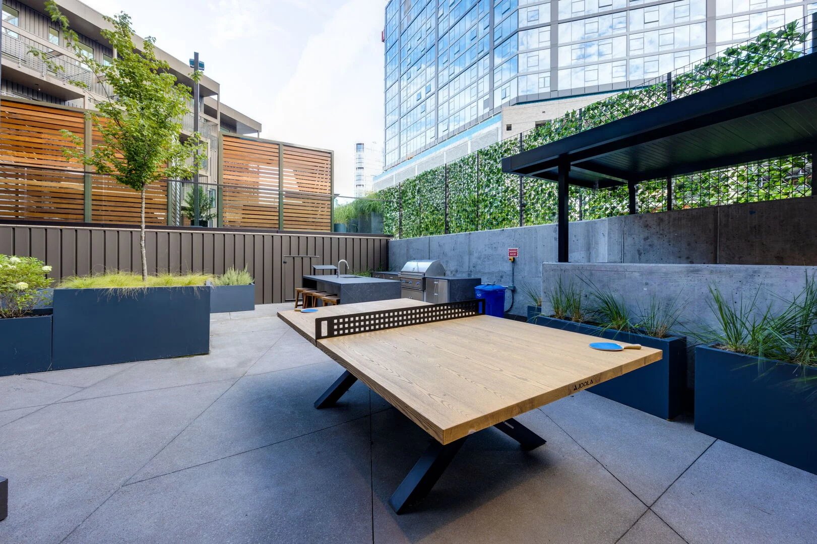 Communal Area: Outdoor furnishings for lounging with a firepit, Ping Pong, and built-in BBQ grill with an outdoor island offering bar seating.