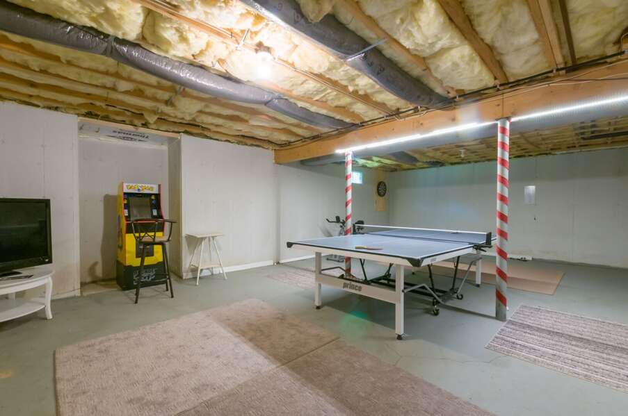 Game room in basement with ping pong, Pac Man, dart board, and exercise bike