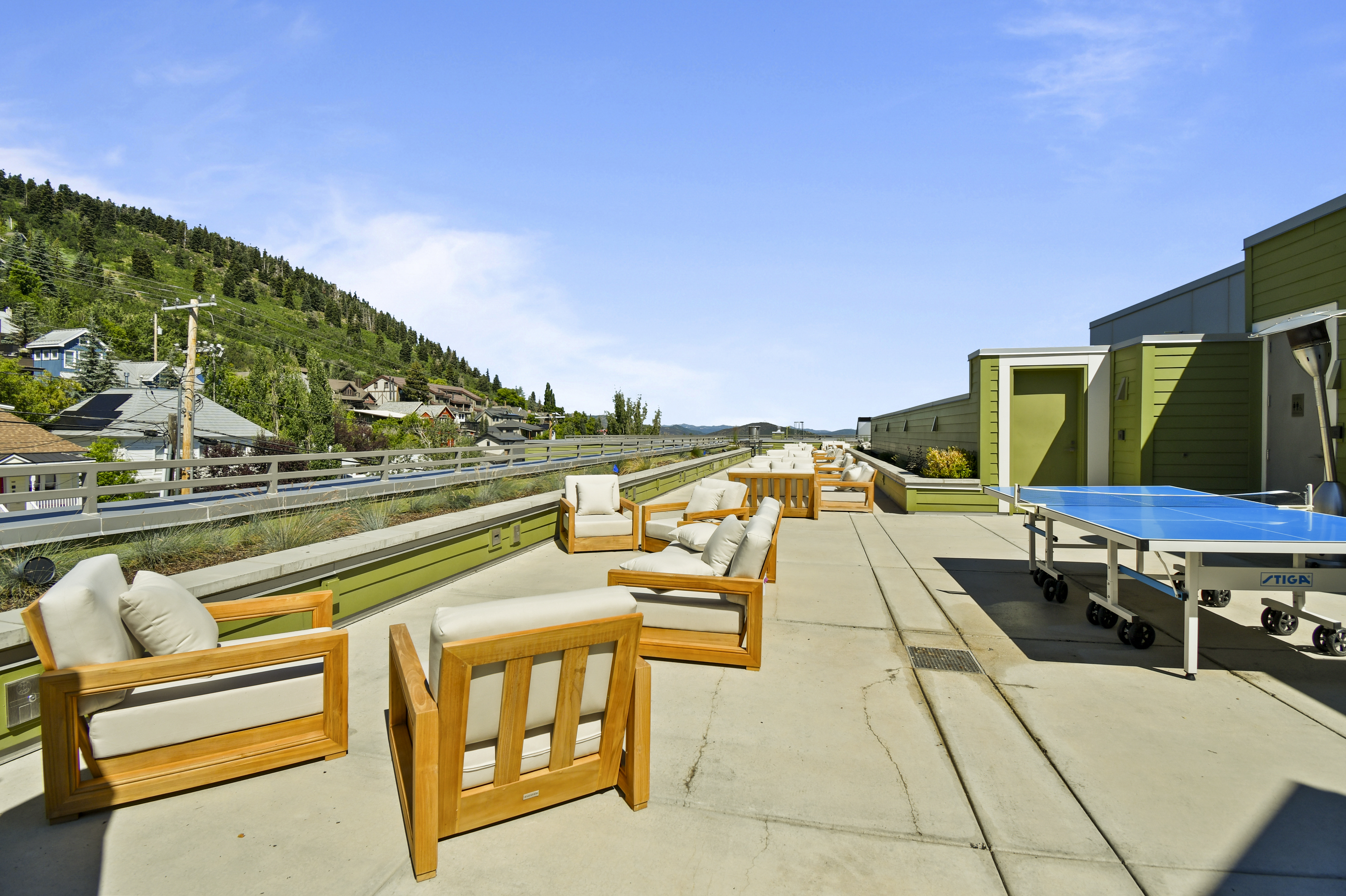 Rooftop balcony with comfortable outdoor furnishings, ping pong tables, dining tables, and a fire pit.