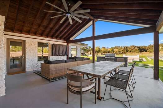 Covered patio with a sectional sofa, smart TV, outdoor dining, and grill with mini fridge