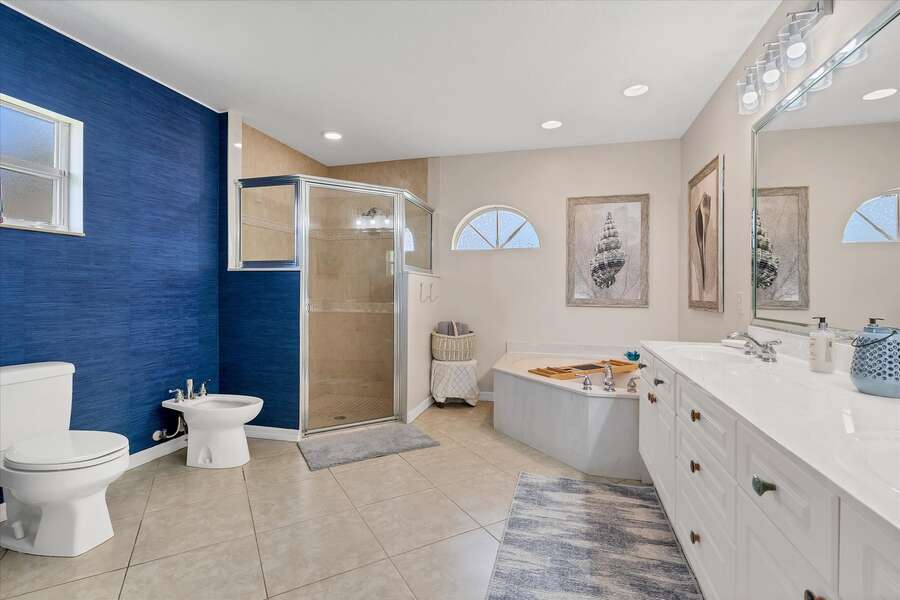 Large, bright ensuite featuring walk-in shower, soaking tub, and bidet