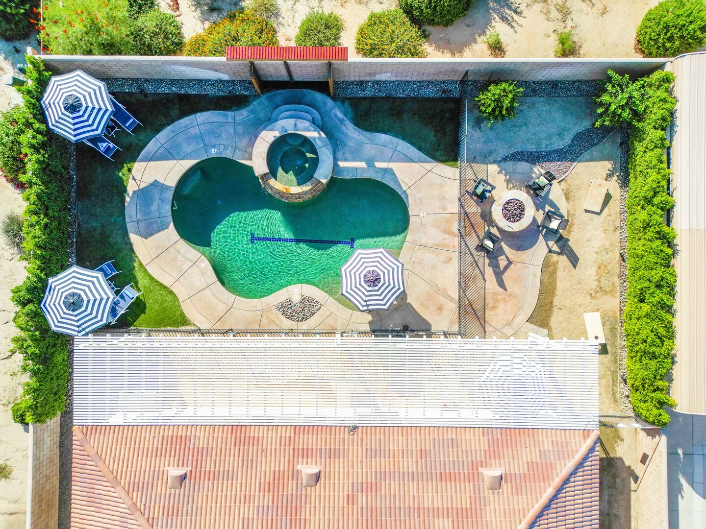 This backyard has it all: pool, warm spa, loungers, shade-providing umbrellas, fire pit, classic game f corn hole, and it's even equipped with a built-in gate, ensuring the safety of your little ones and pets!