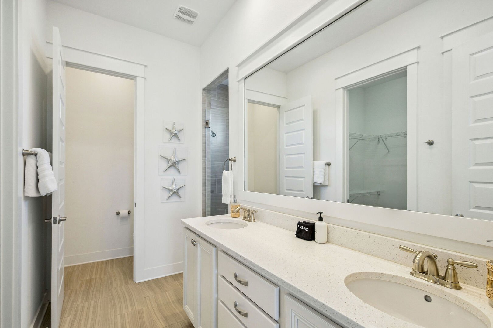 Primary bathroom features a large walk-in closet, dual vanities and a large walk-in shower.