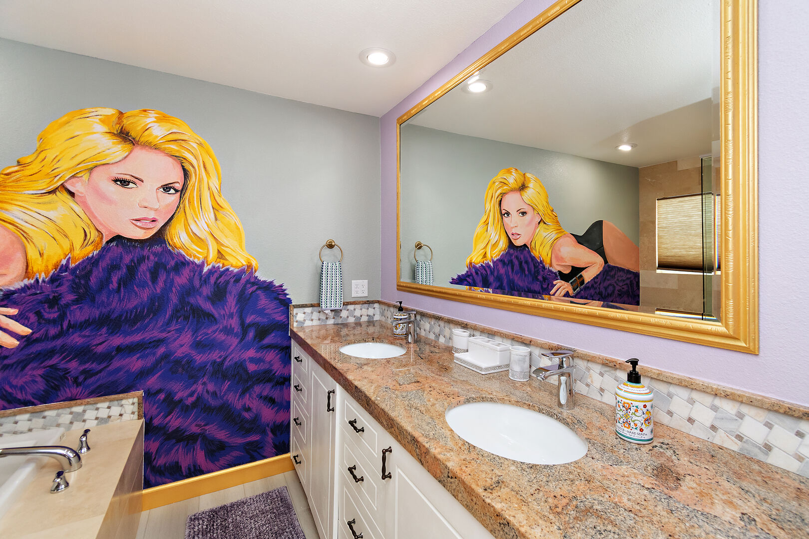 The private, en suite bathroom features a soaking tub, tile shower, and double vanity sinks, while a captivating mural of Shakira adds a unique touch to the space.