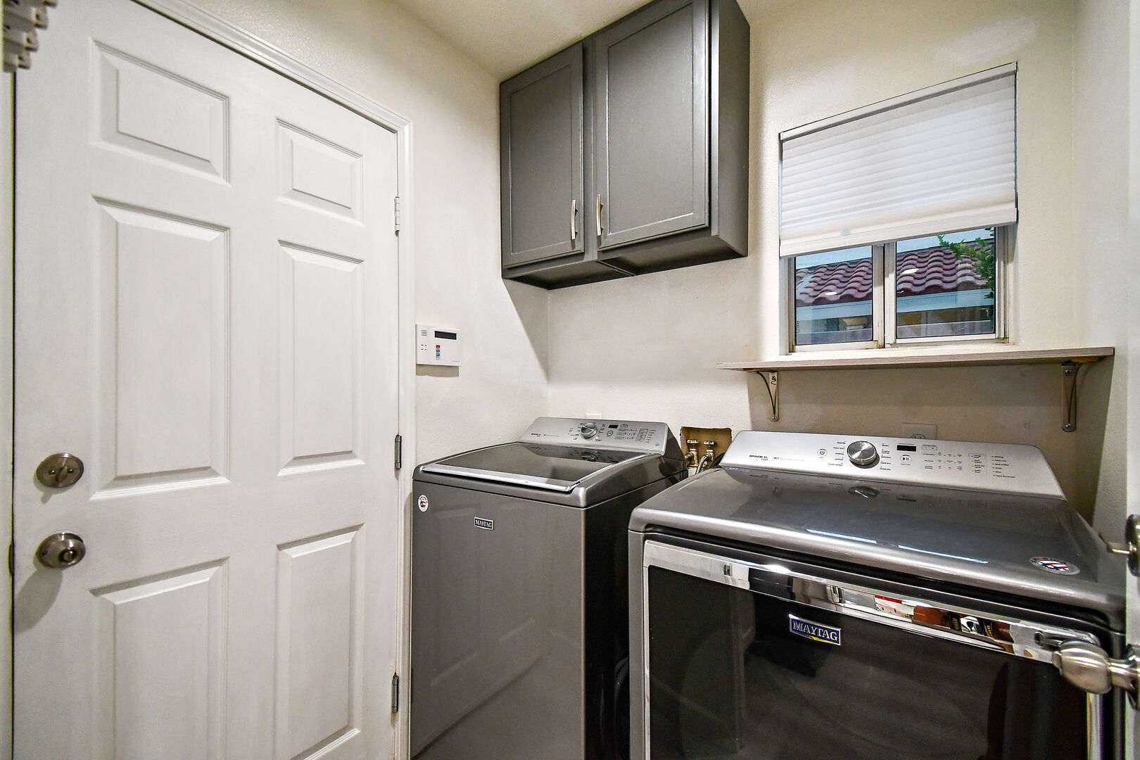 The fully equipped laundry room features a washer, dryer, iron, ironing board, and laundry pods.