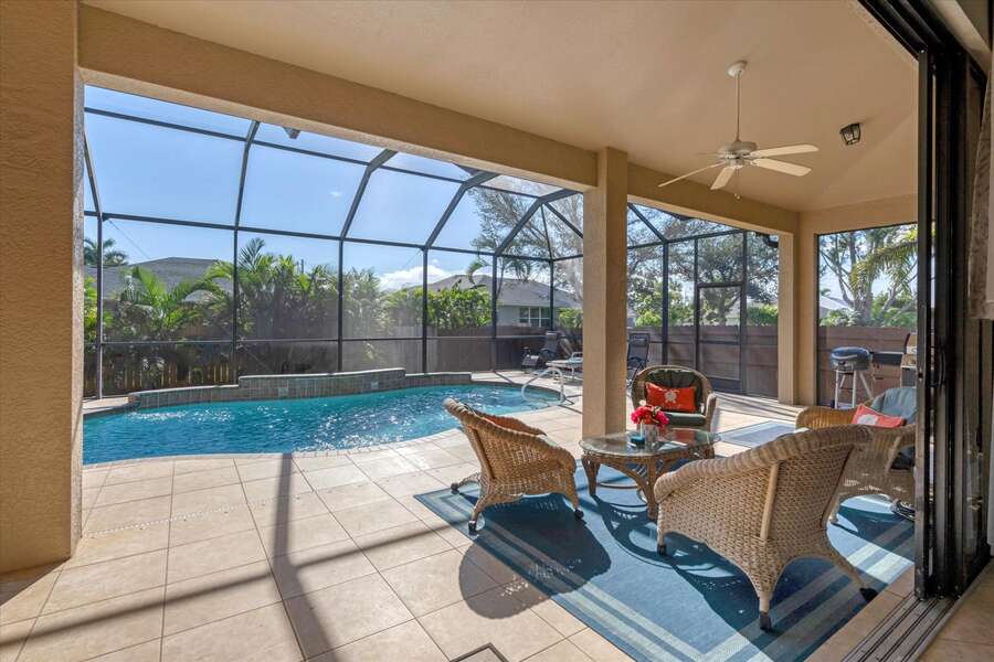 Covered lanai with beuatiful pool and plenty of dining and seating space