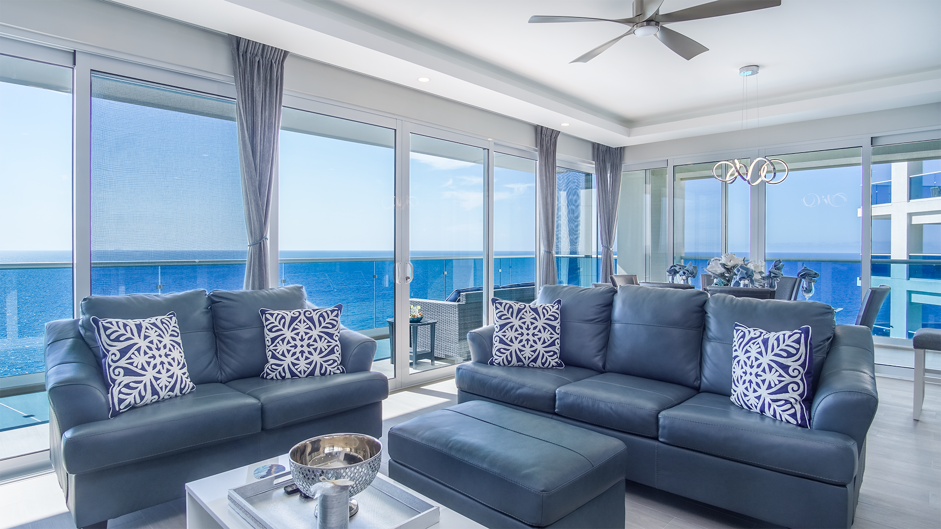 The living room features leather sofas, with tons of beautiful ocean sunlight pouring in.