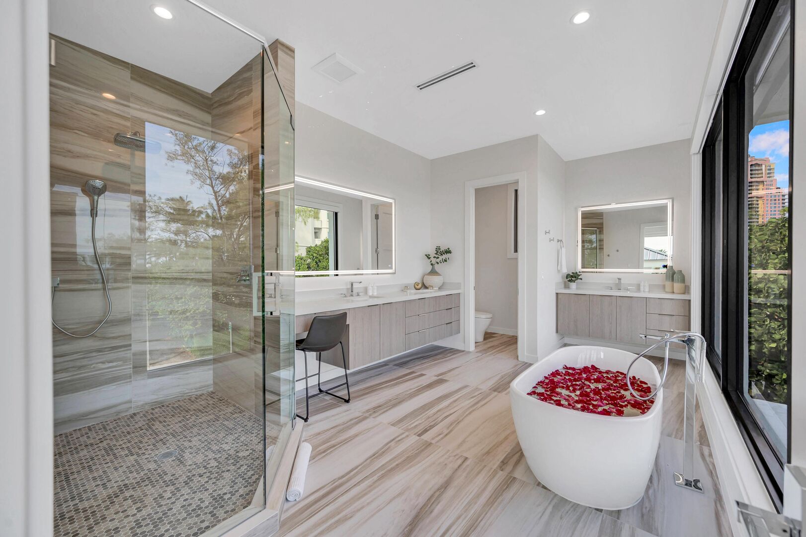 The primary bathroom featuring a bathtub, walk-in shower and two vanities.