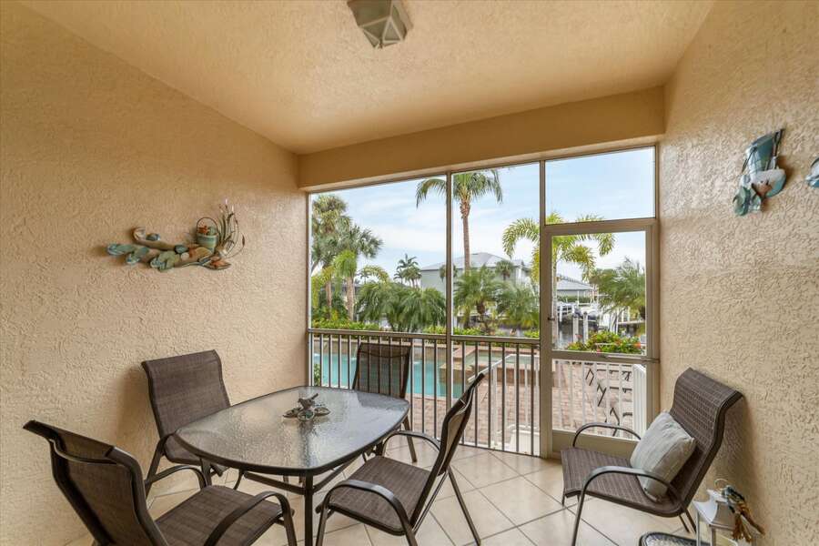 Screened-in patio with outdoor dining overlooking pool & canal