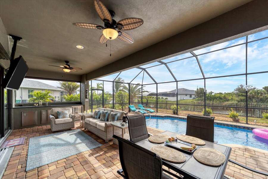 Perfect outdoor space overlooking the pool and canal. Lanai features outdoor kitchen, dining & seating areas, sun loungers & 55-inch Smart TV