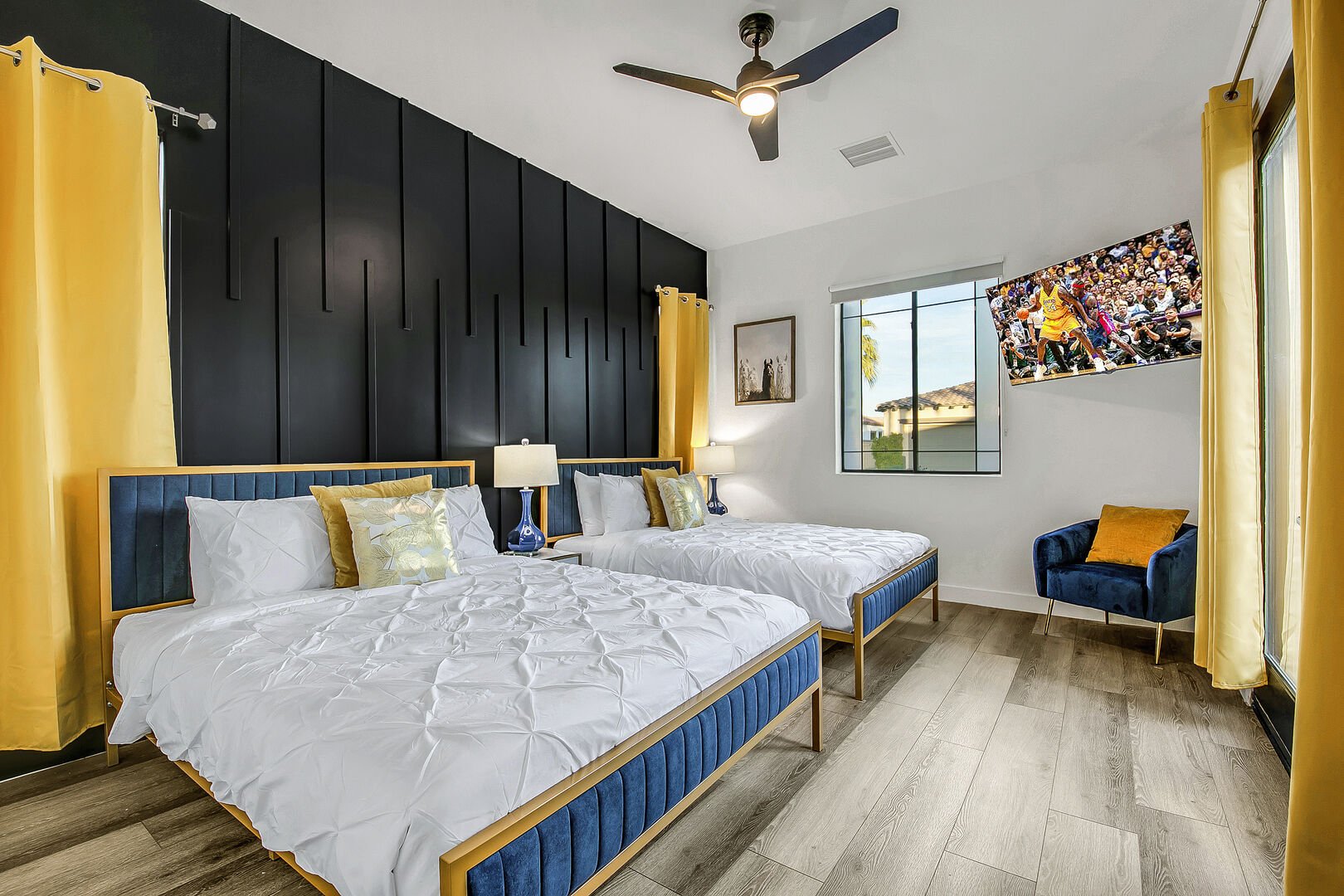 Suite 2 is located to the right of the entrance doors and features two Queen-sized Beds, 55-inch TCL with Roku Smart television, a remote-controlled ceiling fan, and a reach-in closet with access to the front courtyard.
