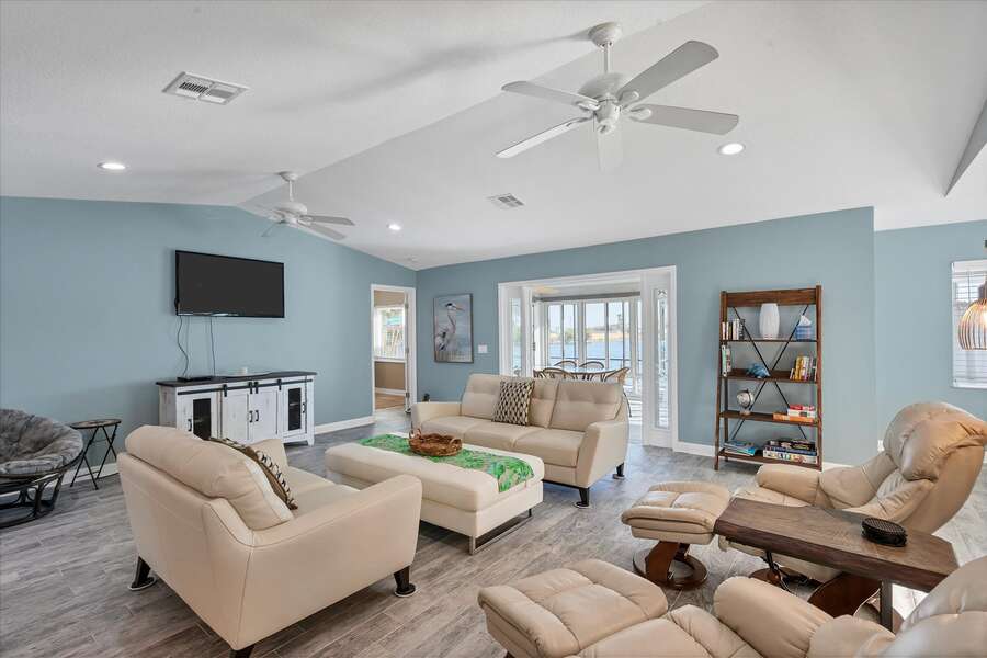 Bright, open living room with view of pool and canal. 50-inch TV