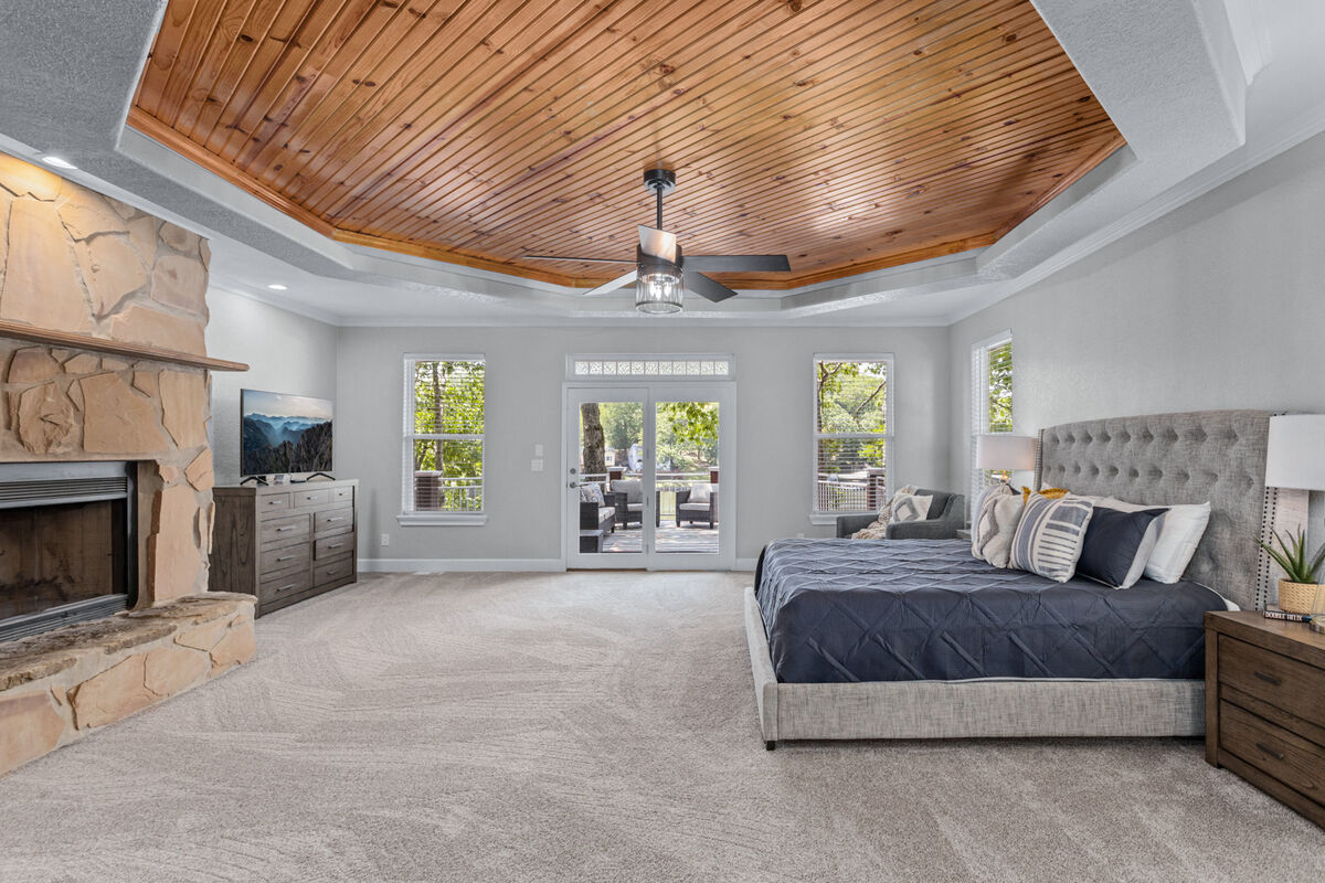 The master bedroom has a stone fireplace for warm and cozy nights, a coffered ceiling, a view of the lake and an access to the main upper level balcony.