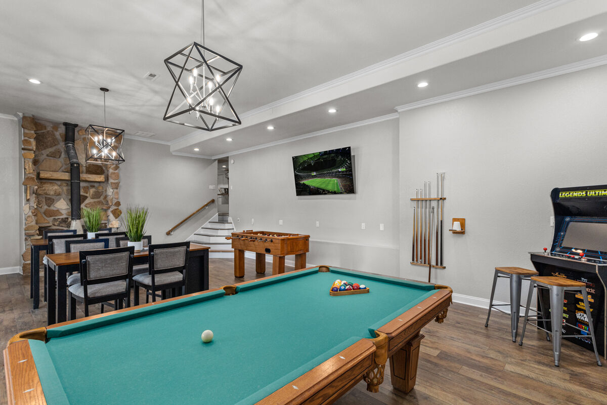 Large gaming room with stand up video arcade, foosball, pool table, corn hole for rear deck, 2 tables for board games and card games.
