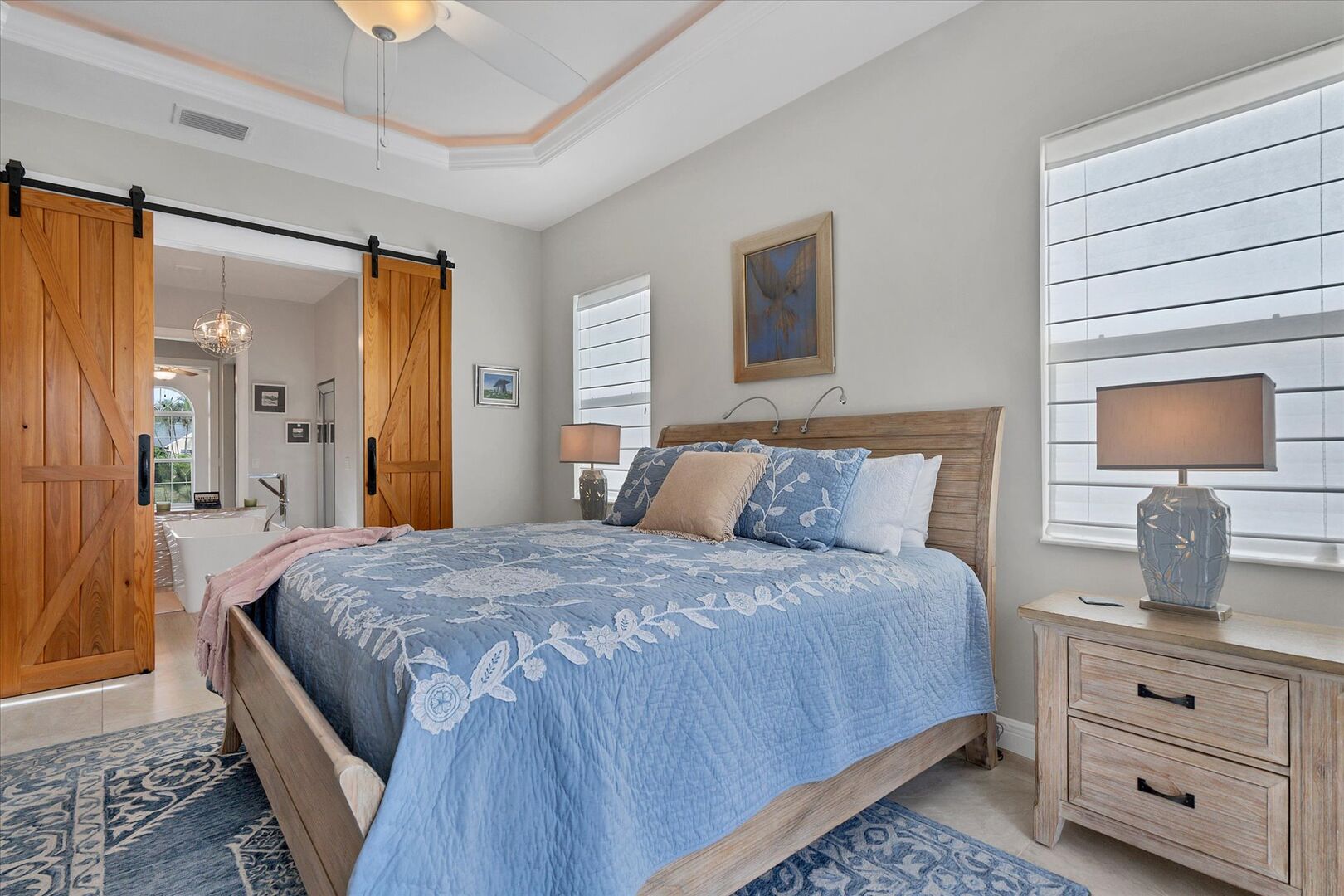 Primary bedroom featuring king bed, lanai doors and gorgeous barn doors leading to ensuite