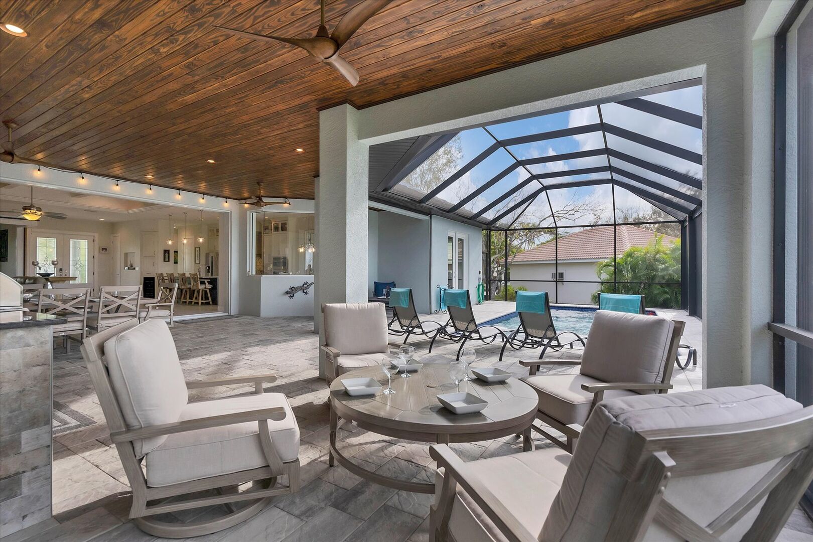 Incredible lanai overlooking canal with outdoor dining, kitchen, fire pit table, and sparkling pool