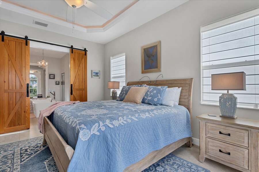 Primary bedroom featuring king bed, lanai doors and gorgeous barn doors leading to ensuite