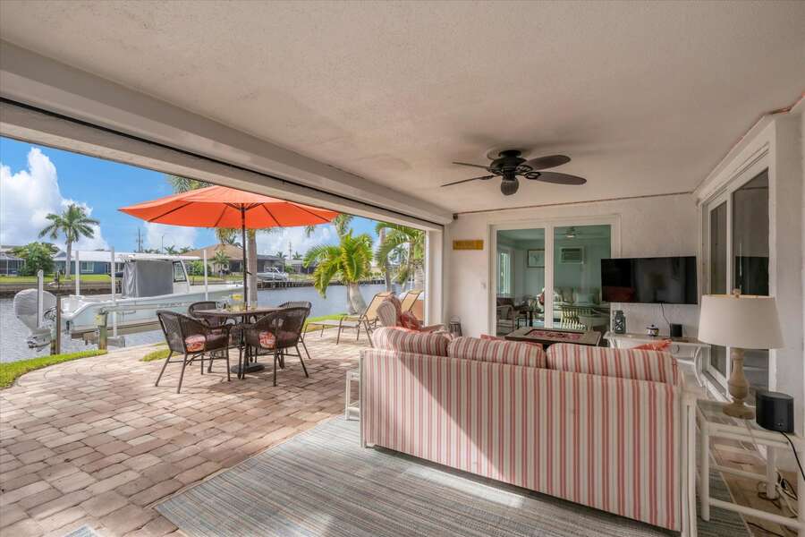 Spacious outdoor area with hot tub, conversation seating area with fire pit coffee table, and dining table overlooking the water. Lanai also features a propane BBQ grill
