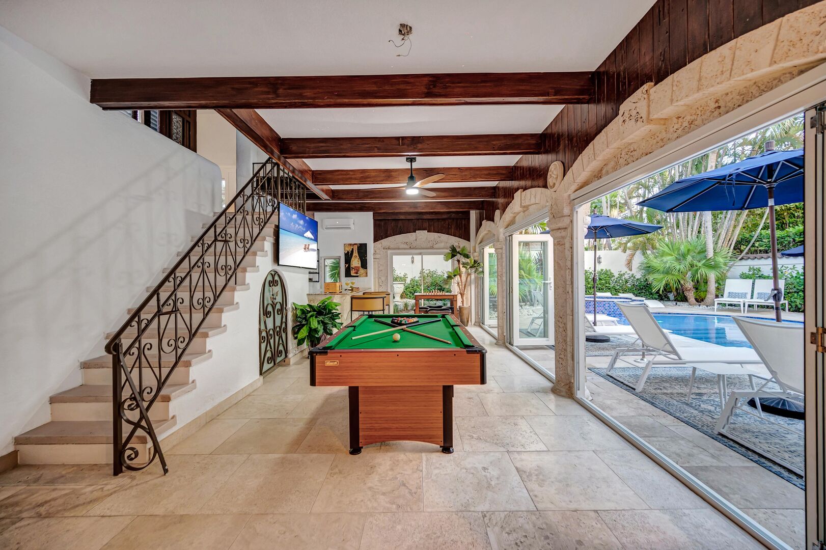 The covered patio, featuring a bar area with a pool table, provides seamless access to the heated pool and bedroom six on the second floor