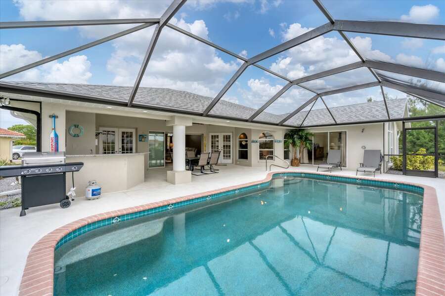Spacious outdoor area with propane grill and dining table overlooking the sparkling pool & canal. Lanai also includes and half bath and outdoor shower.