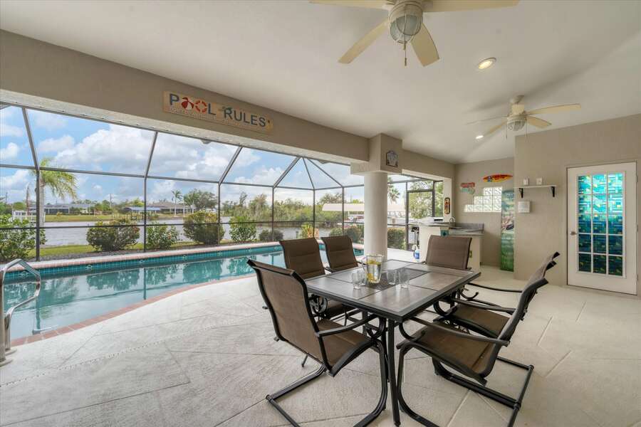 Spacious outdoor area with dining table overlooking the pool & canal