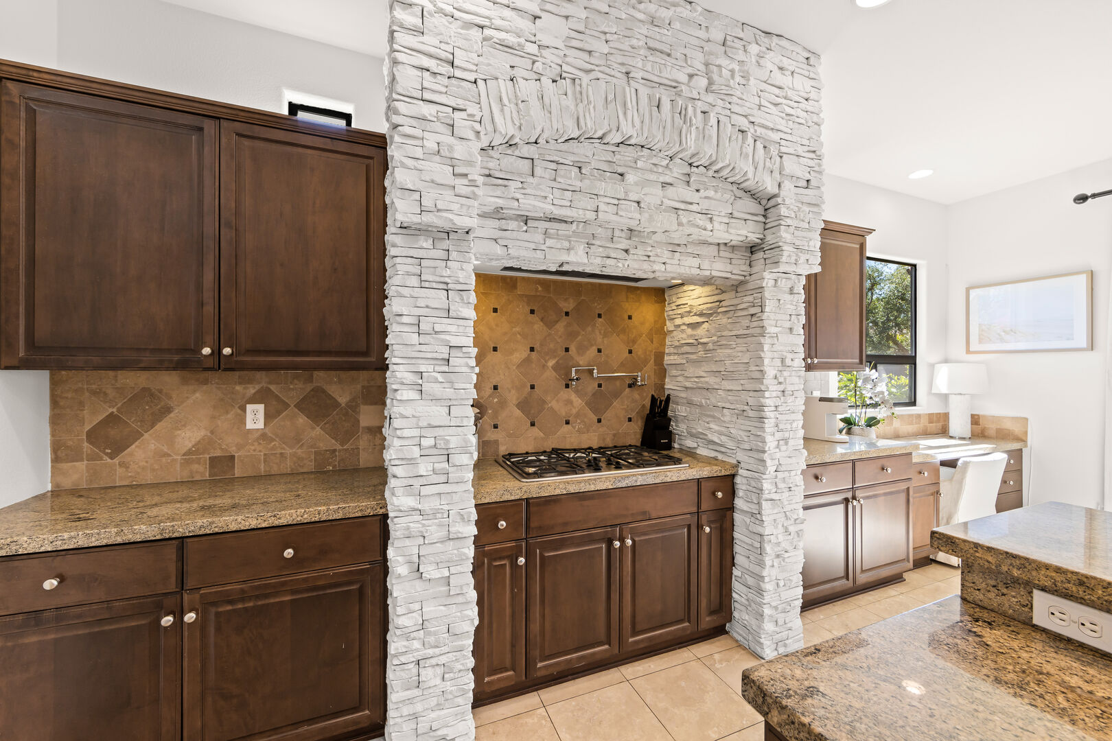 The gourmet kitchen is a chef's dream, boasting a cooktop with 5 burners and a convenient pot filler, all surrounded by exquisite stone to elevate your cooking experience.
