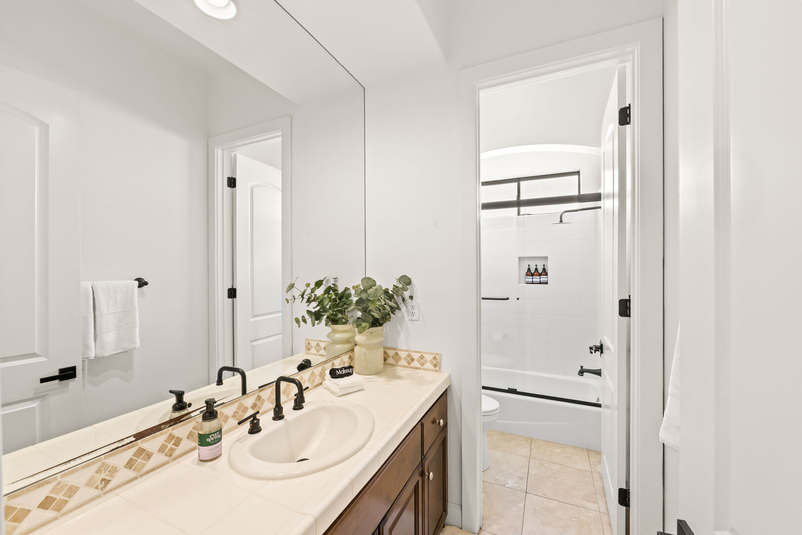 The hallway bathroom is located next to the laundry room and features a bathtub shower combo with a decorative vanity sink.